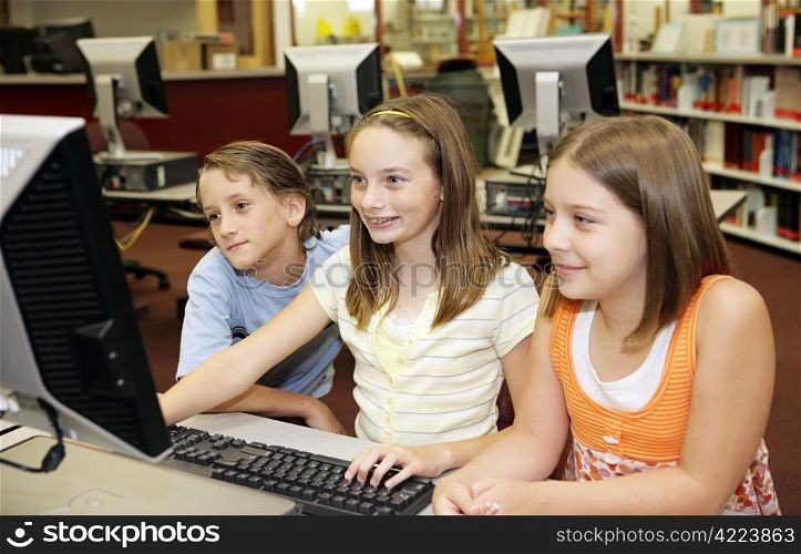 A group of school children having fun working on a computer in the school media center.