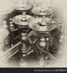 A group of shisha (hubble-bubble) pipes in a souq in Doha, Qatar. Photographed on medium format black and white film with antique toning and fading added in processing.