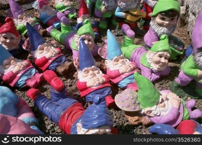 A group of small garden gnomes scattered on the ground take a number of different positions - some sleeping, some lying down, and some sitting.