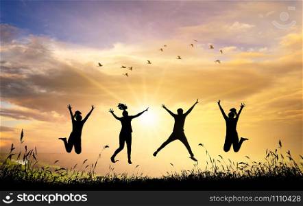 A group of teenage children are jumping and having fun during the setting sun. Backlit corner