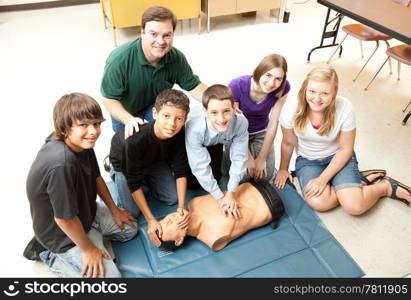 A group of teenage students learning CPR life saving techniques in class.