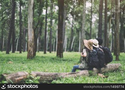 A group of travelers sitting on a log and looking into a beautiful pine woods