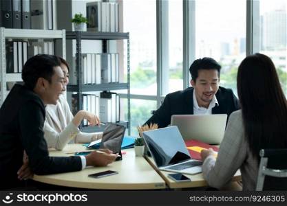 A group of young Asian entrepreneurs. Top Management is meeting to review stock investment data from the team in a meeting room with natural light windows.