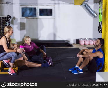 a group of young athletes sitting on the floor and relaxing after exercise at crossfitness gym. young athletes sitting on the floor and relaxing