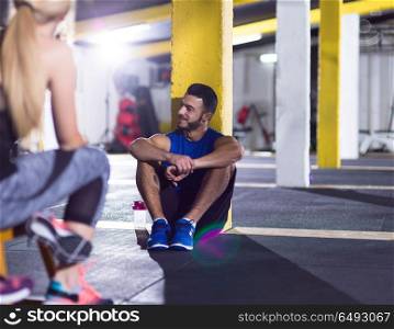 a group of young athletes sitting on the floor and relaxing after exercise at crossfitness gym. young athletes sitting on the floor and relaxing