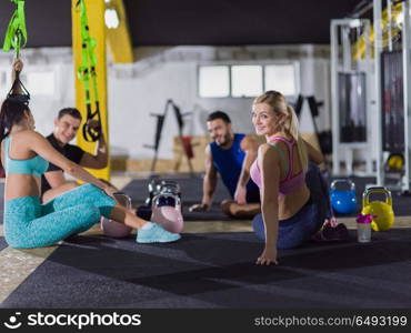 a group of young athletes sitting on the floor and relaxing after exercise at crossfitness gym. young athletes sitting on the floor and relaxing