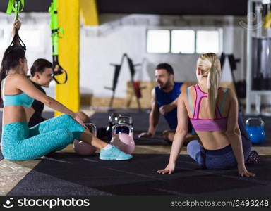 a group of young athletes sitting on the floor and relaxing after exercise at crossfitness gym. young athletes sitting on the floor and relaxing