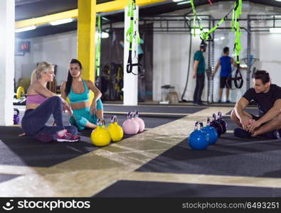 a group of young athletes sitting on the floor and relaxing after exercise at crossfitness gym. young athletes sitting on the floor and relaxing