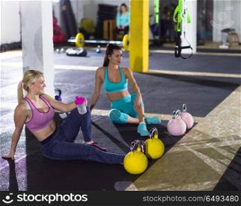 a group of young athletes sitting on the floor and relaxing after exercise at crossfitness gym. young athletes sitting on the floor and relaxing