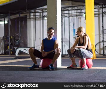 a group of young athletes sitting on the medical bal and relaxing after exercise at crossfitness gym. young athletes sitting on the crossfitness ball and relaxing