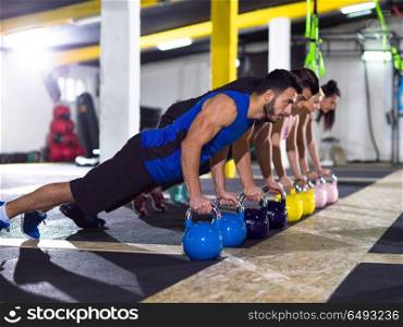 a group of young healthy athletes doing pushups with kettlebells at crossfitness gym. young athletes doing pushups with kettlebells
