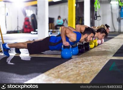 a group of young healthy athletes doing pushups with kettlebells at crossfitness gym. young athletes doing pushups with kettlebells