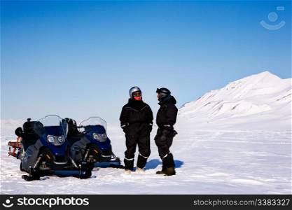 A group on a winter snowmobile adventure over a barren winter landscape
