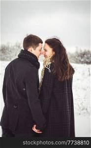 A guy and a girl in warm clothes and scarves on a walk in the snowy forest and in the field