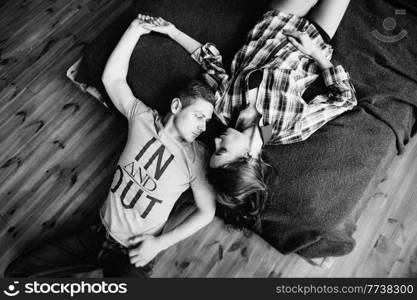 a guy and a girl lie on the bed in the room and look at each other