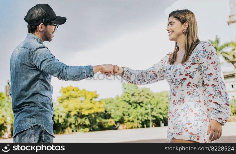 A guy and girl shaking hands on the street. Two young smiling teenagers shaking hands in the street. Concept of man and woman shaking hands on the street.