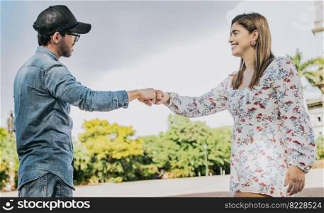 A guy and girl shaking hands on the street. Two young smiling teenagers shaking hands in the street. Concept of man and woman shaking hands on the street.