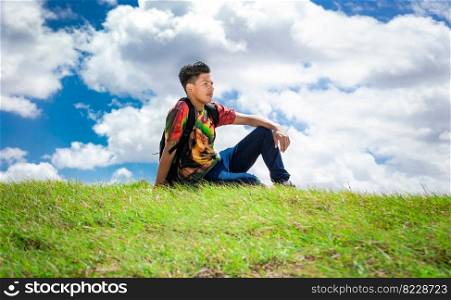 A guy sitting on a hill enjoying the scenery, tourist sitting on a hill enjoying the scenery