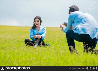 A guy taking a picture of a girl in the field, Boyfriend taking a picture of his girlfriend in the field, Two friends taking photos with the cell phone in the field