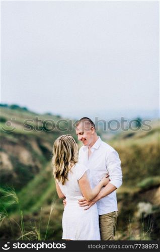 a guy with a girl in light clothes on the background of a green canyon of erosion of the earth