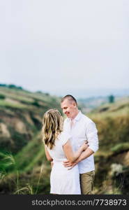 a guy with a girl in light clothes on the background of a green canyon of erosion of the earth