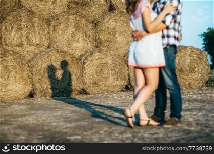 a guy with a girl on a summer walk in the field near round haystacks