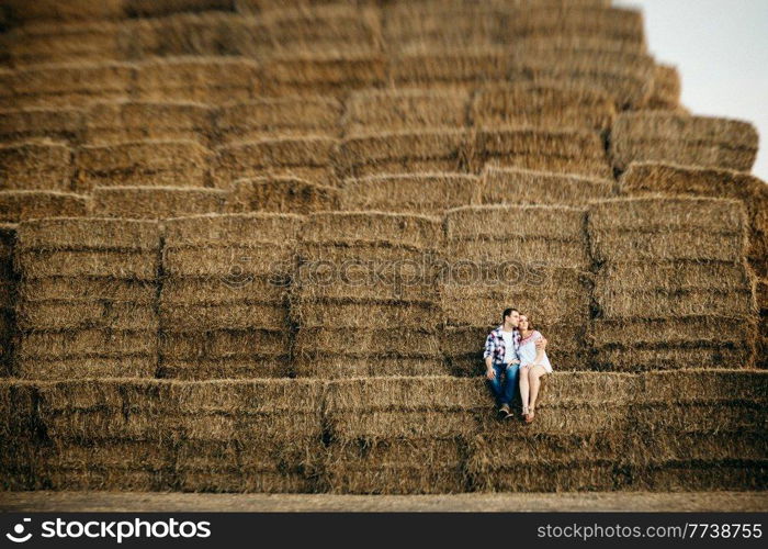 a guy with a girl on a summer walk in the field near round haystacks