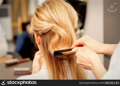 A hairdresser is combing female hairstyling in a hairdressing beauty salon. A hairdresser is combing female hairstyling in a hairdressing beauty salon.