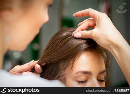 A hairdresser is making the hairstyle of a young brunette woman in a hair salon, close up. A hairdresser is making the hairstyle of a young brunette woman in a hair salon, close up.