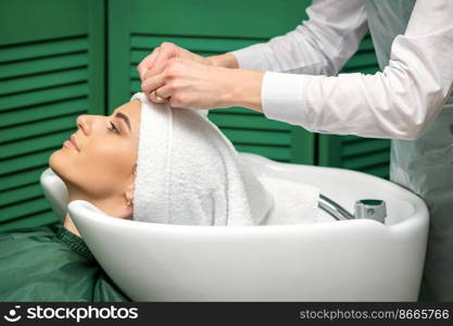 A hairdresser is wrapping a female head in a towel after washing hair in the beauty salon. A hairdresser is wrapping a female head in a towel after washing hair in the beauty salon.