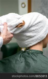 A hairdresser is wrapping the wet hair of the young woman in a towel after washing at the beauty salon. A hairdresser is wrapping the wet hair of the young woman in a towel after washing at the beauty salon.