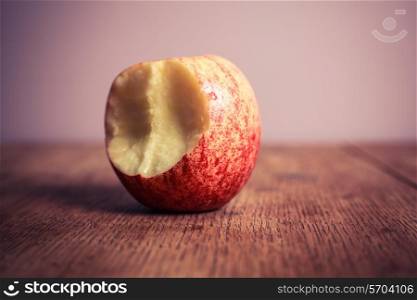 A half eaten apple on a wooden table
