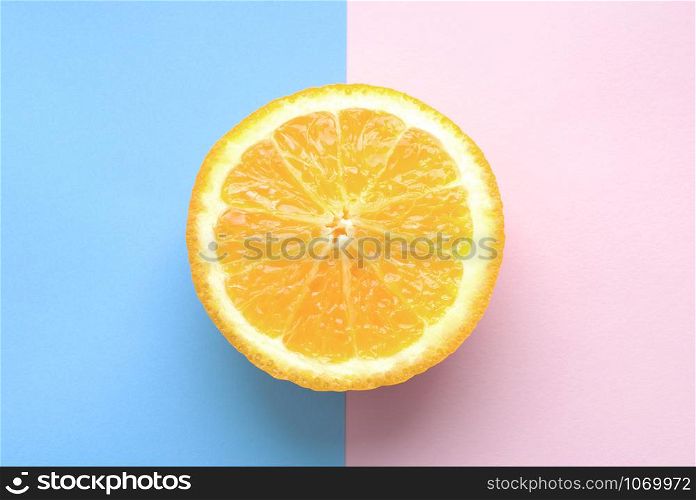 A half lemon piece on a pink and blue background.