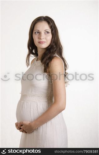 A half-length portrait of a pregnant girl in a beige tight dress