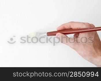 A hand holding a brush on white