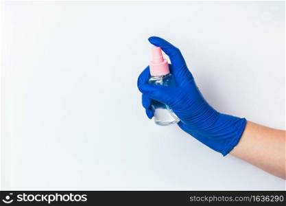 A hand in a blue latex glove holds a disinfectant. The concept of preventive protection against coronavirus. Use of antiseptics for cleaning.. A hand in a blue latex glove holds a disinfectant. The concept of preventive protection against coronavirus.