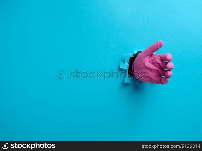 a hand in a pink latex glove holds an object, a part of the body sticks out of a torn hole in a blue paper background
