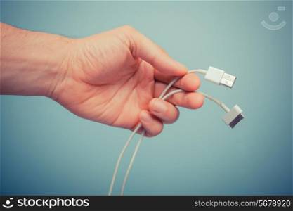 A hand is holding a charging cable for a smart phone