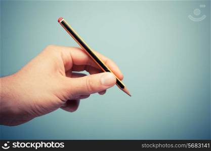 A hand is holding a pencil
