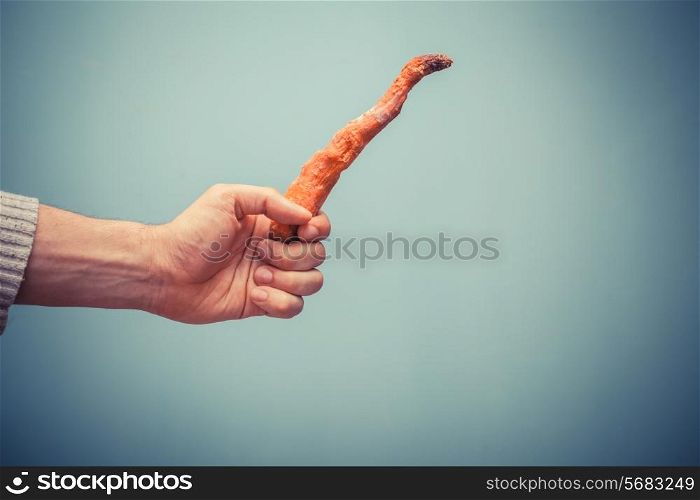 A hand is holding a rotten carrot