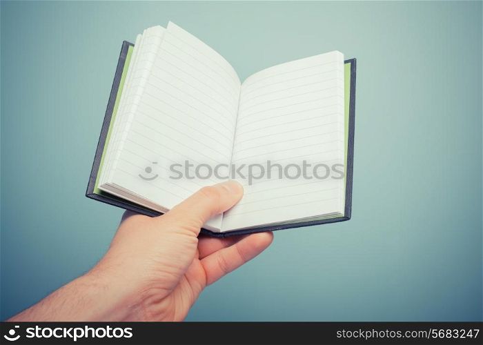 A hand is holding a small notebook