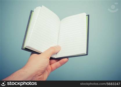 A hand is holding a small notebook