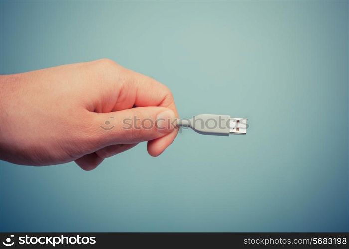 A hand is holding a usb computer cable