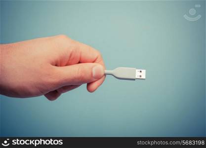 A hand is holding a usb computer cable