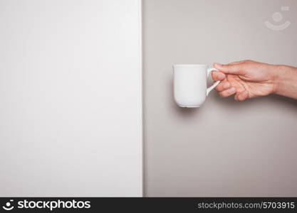 A Hand is holding a white cup against a green and white background