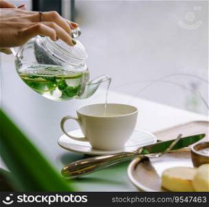 A hand pouring tea from glass teapot