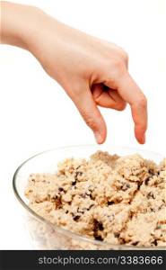 A hand reaching for a bowl of raw cookie dough