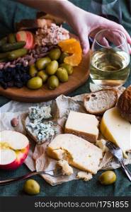 A hand reaching for white wine in a cheese board spread