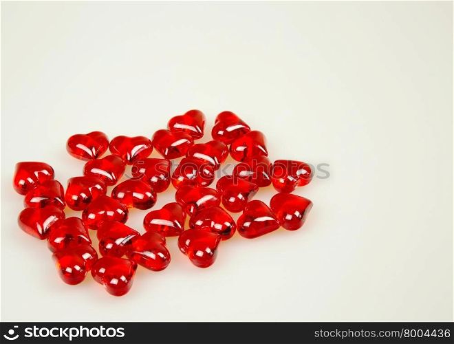 A handful of thirty-red stones in the shape of hearts isolated on white background with space for additional text. Horizontal view.