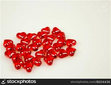 A handful of thirty-red stones in the shape of hearts isolated on white background with space for additional text. Horizontal view.